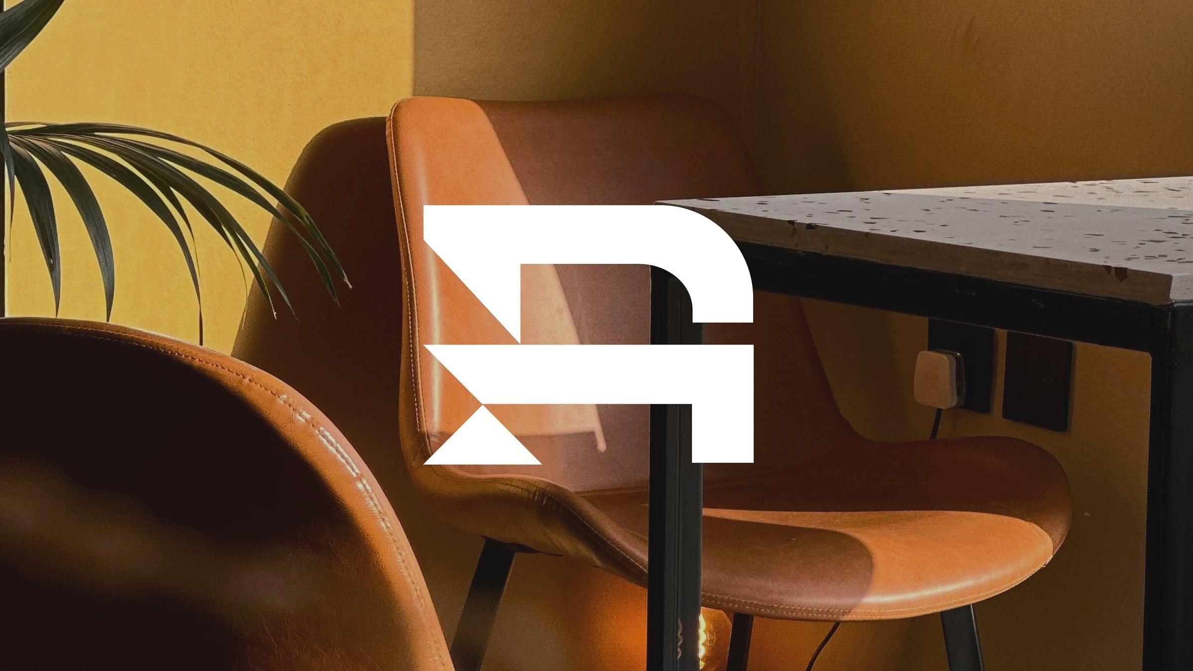 RMC Interiors: a leather lounge chair in warm light beside the RMC logomark